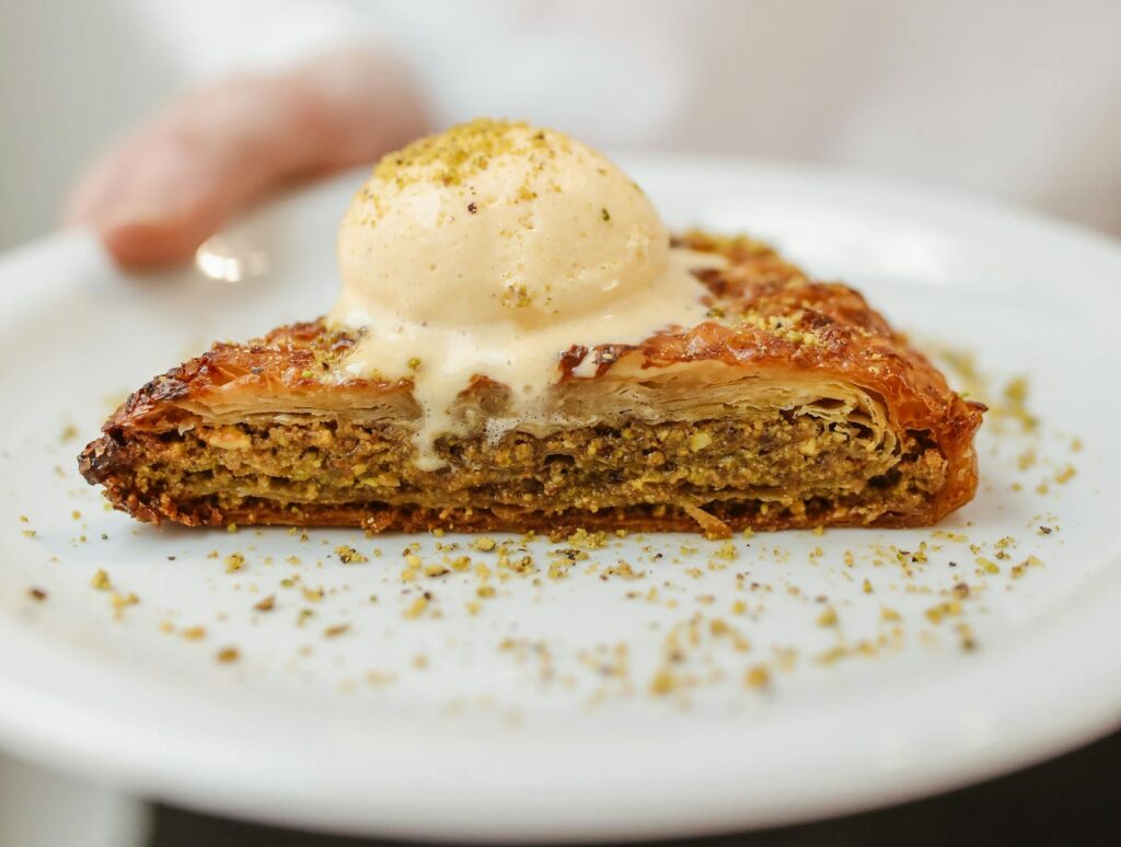 A delectable slice of baklava topped with ice cream, served on a ceramic plate.