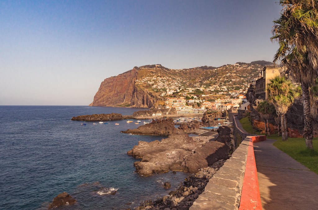 Breathtaking view of Madeira's rocky coast and vibrant townscape at sunrise.