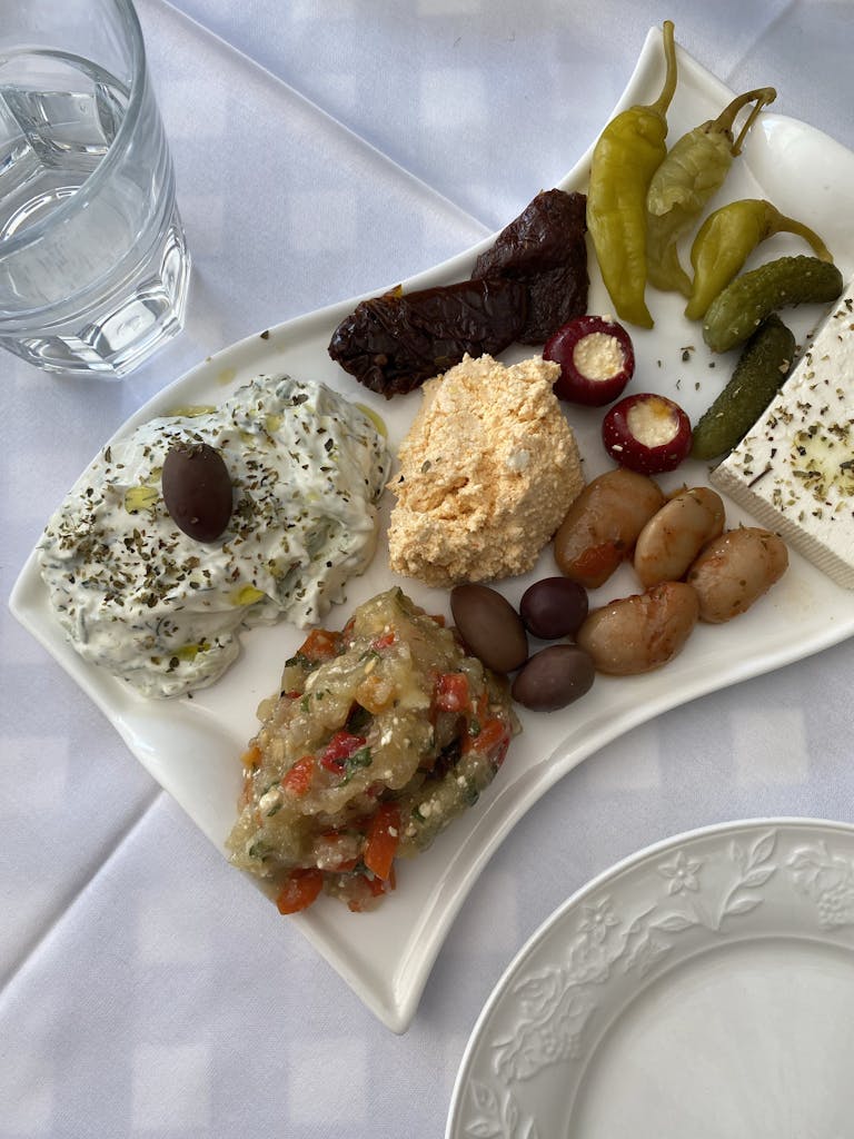 Colorful Mediterranean platter with olives, cheese, and peppers on a white tablecloth setting in Moscow.